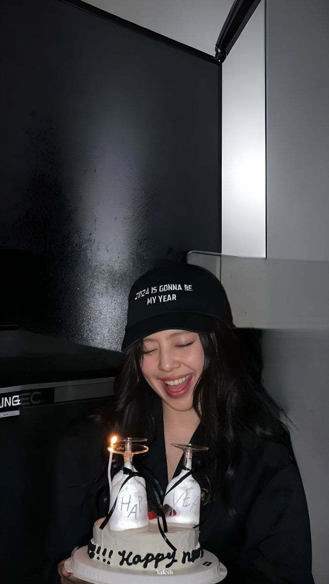 a woman holding a cake with two candles in it