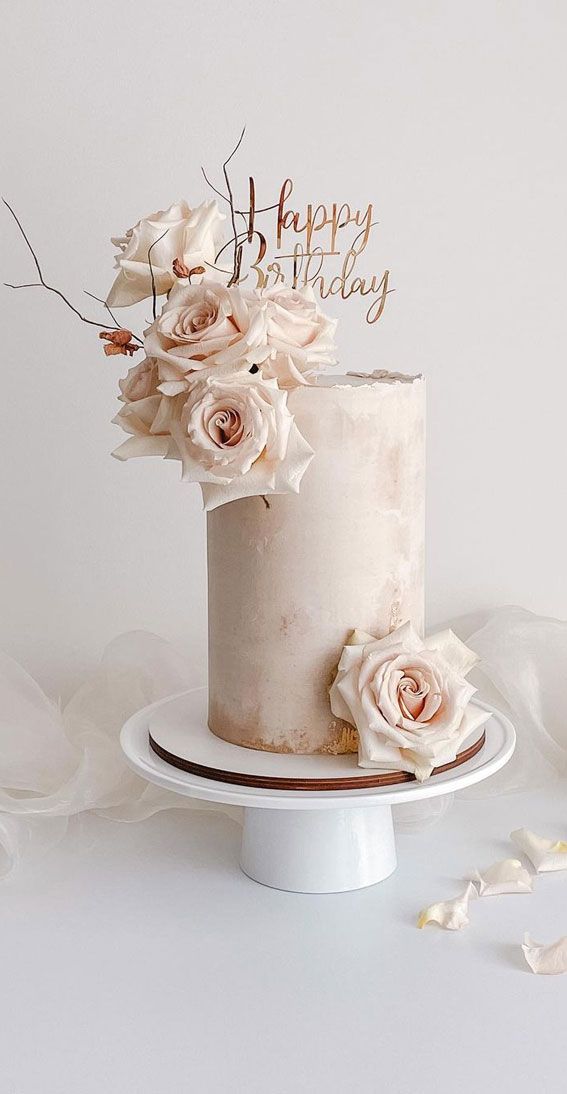 a birthday cake decorated with flowers and the words happy birthday on top is sitting on a plate