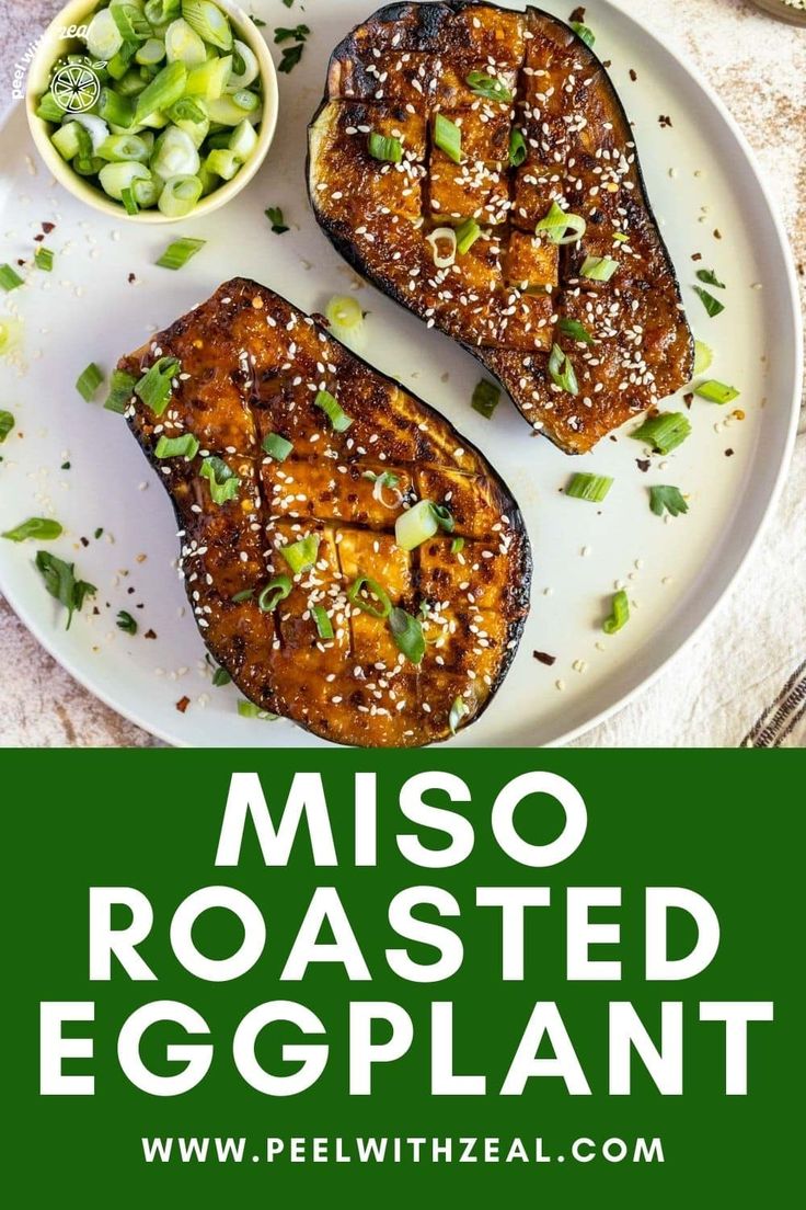 two pieces of grilled eggplant on a white plate with green onions and seasoning