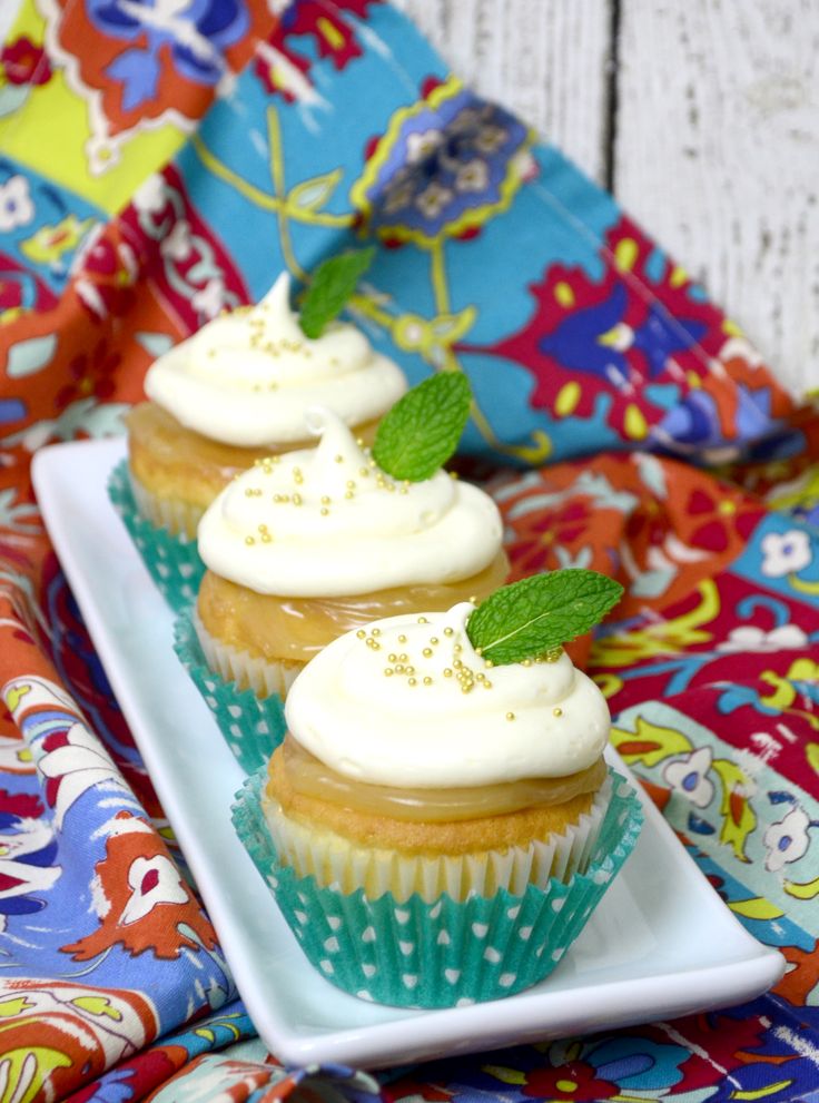 three cupcakes with white frosting and mint sprinkles