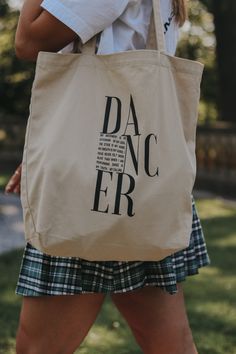 a woman carrying a tote bag with the words dac er printed on it