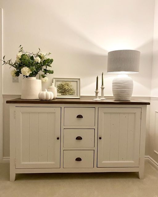 a white cabinet with drawers and vases on top