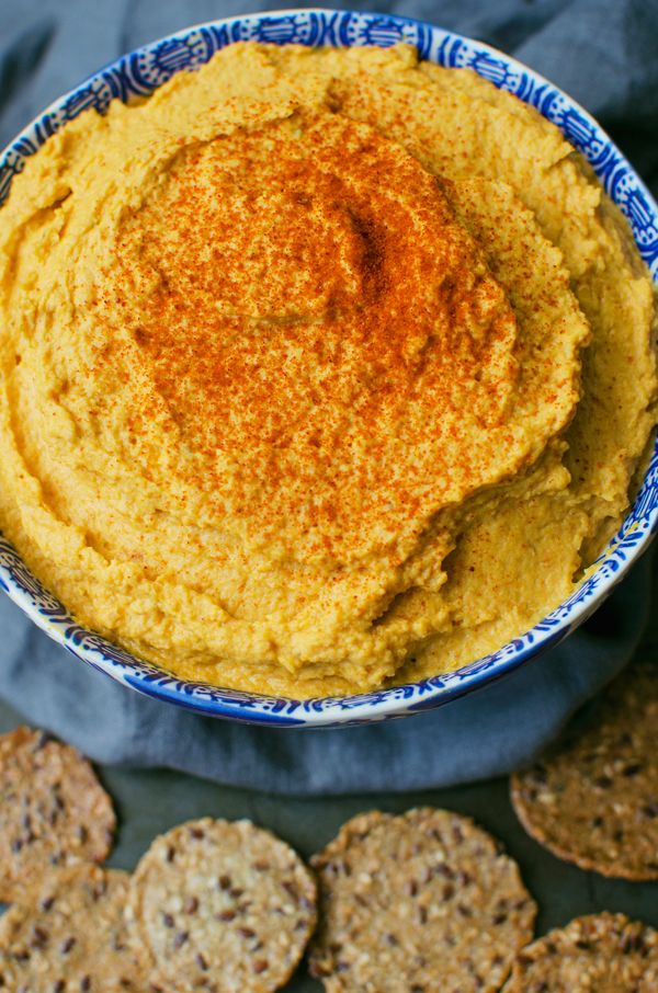 a bowl filled with hummus and crackers on top of a blue table cloth