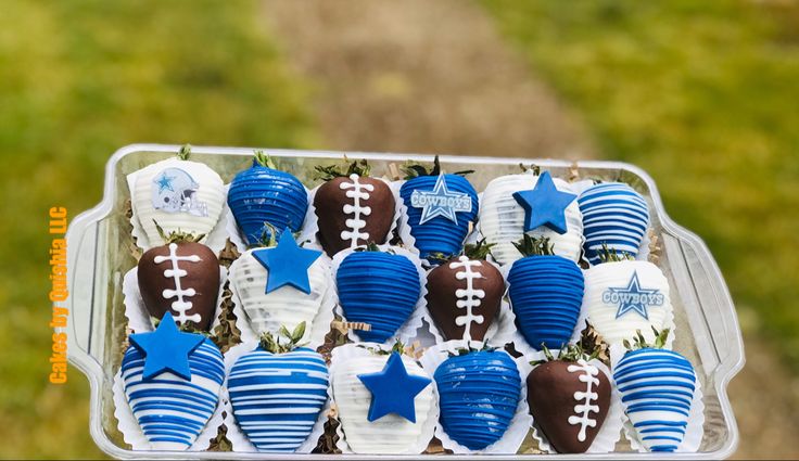 chocolate covered strawberries are arranged in the shape of footballs with blue and white decorations