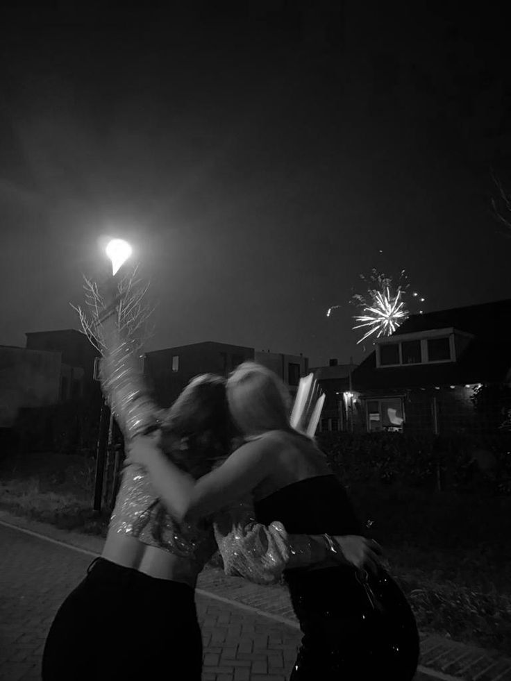 two women are hugging in the street at night