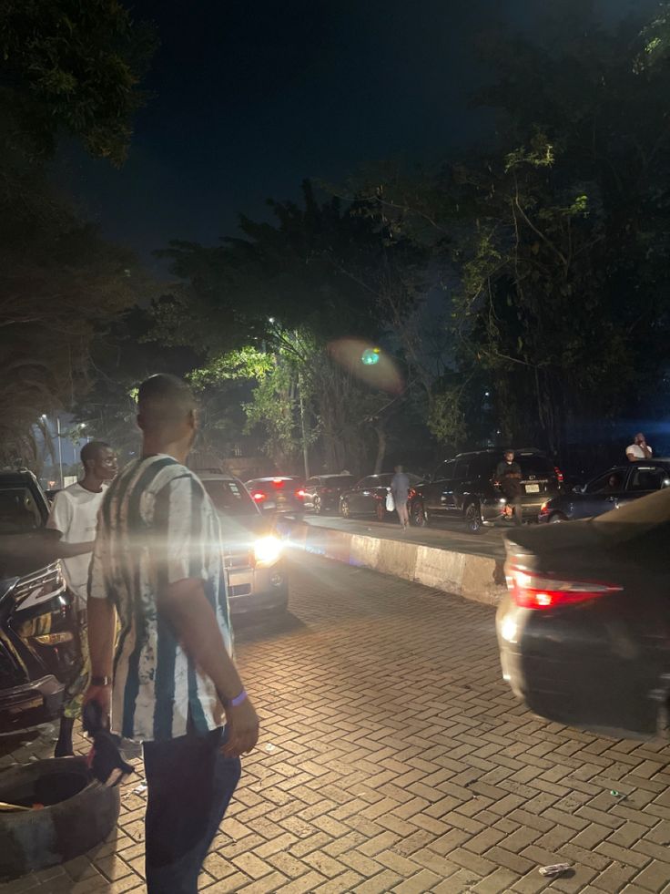 a man standing on the side of a road next to a bunch of parked cars