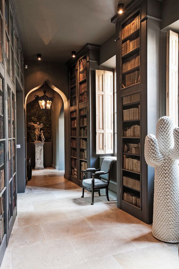 a large room with many bookshelves and chairs in front of the doors that lead to another room