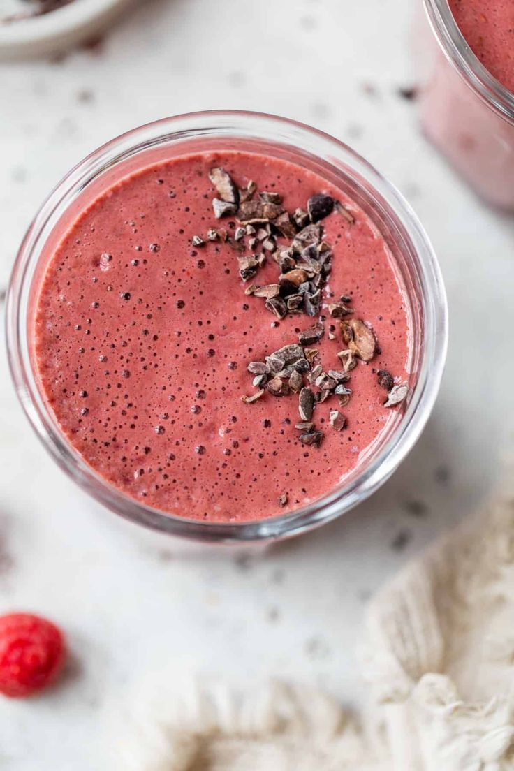 two glasses filled with raspberry smoothie on top of a white countertop