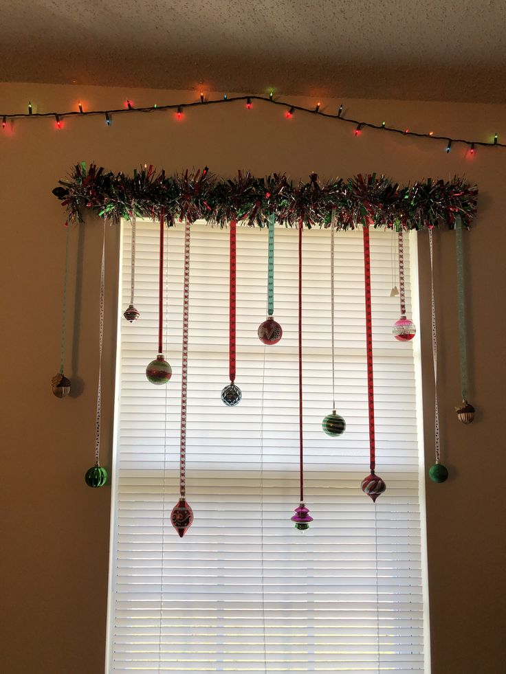 a window with christmas decorations hanging from it's sides and lights on the windowsill