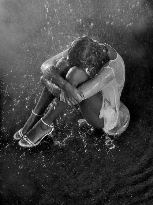 black and white photograph of a person sitting in the rain