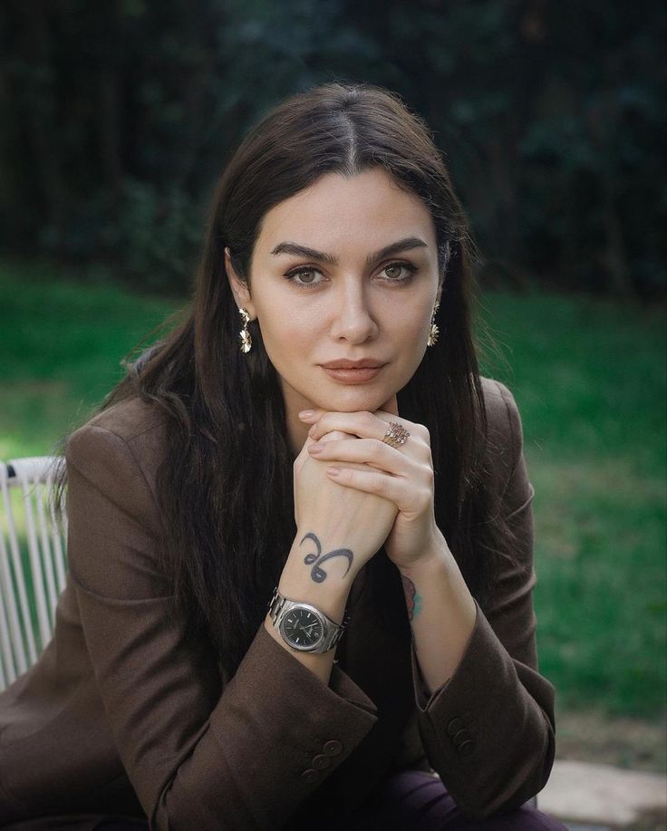 a woman is sitting on a bench with her arms crossed and looking at the camera