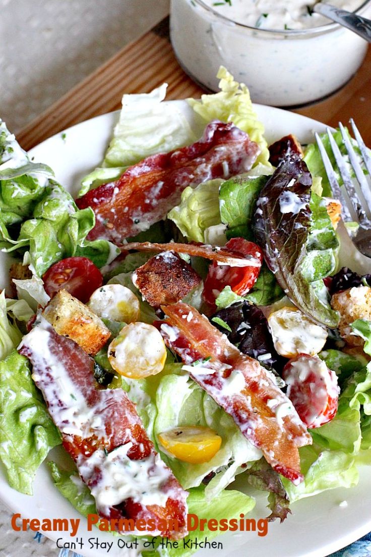 a salad with bacon, lettuce and tomatoes on it is ready to be eaten