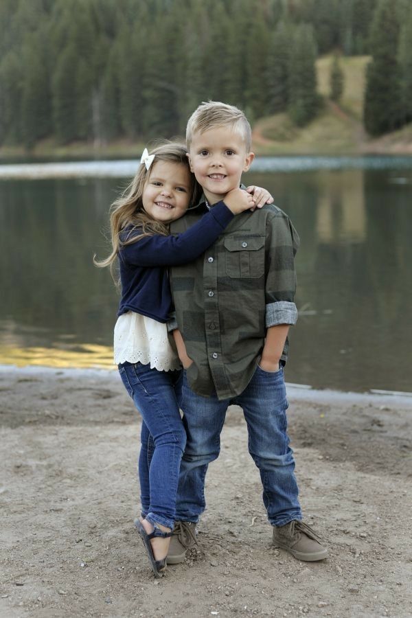 two children hugging each other in front of a lake