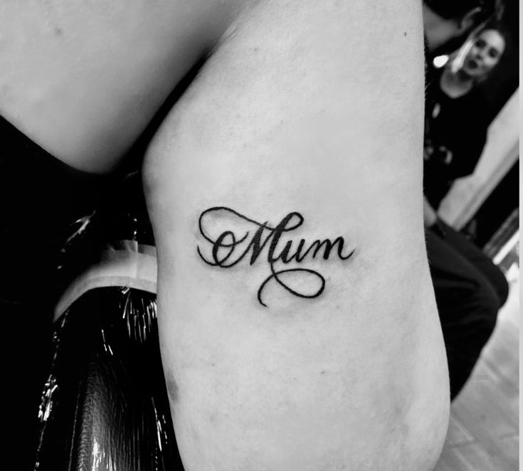 a black and white photo of a woman's arm with the word mum tattooed on it