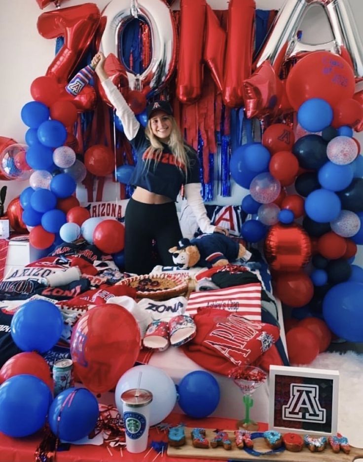 a woman standing in front of a table with red, white and blue balloons