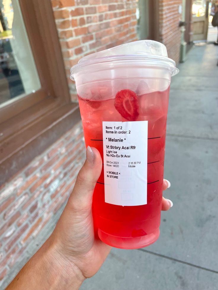 a person holding up a plastic cup filled with liquid