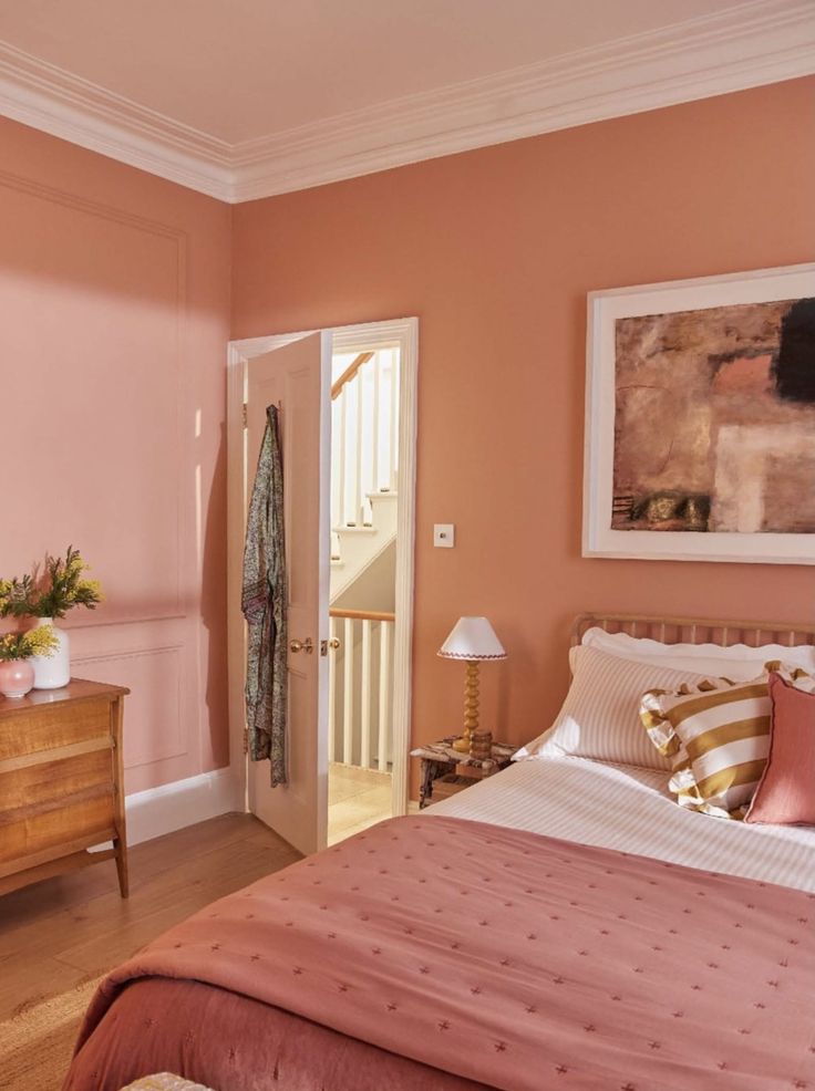 a bedroom with pink walls and bedding in the center, two nightstands on either side