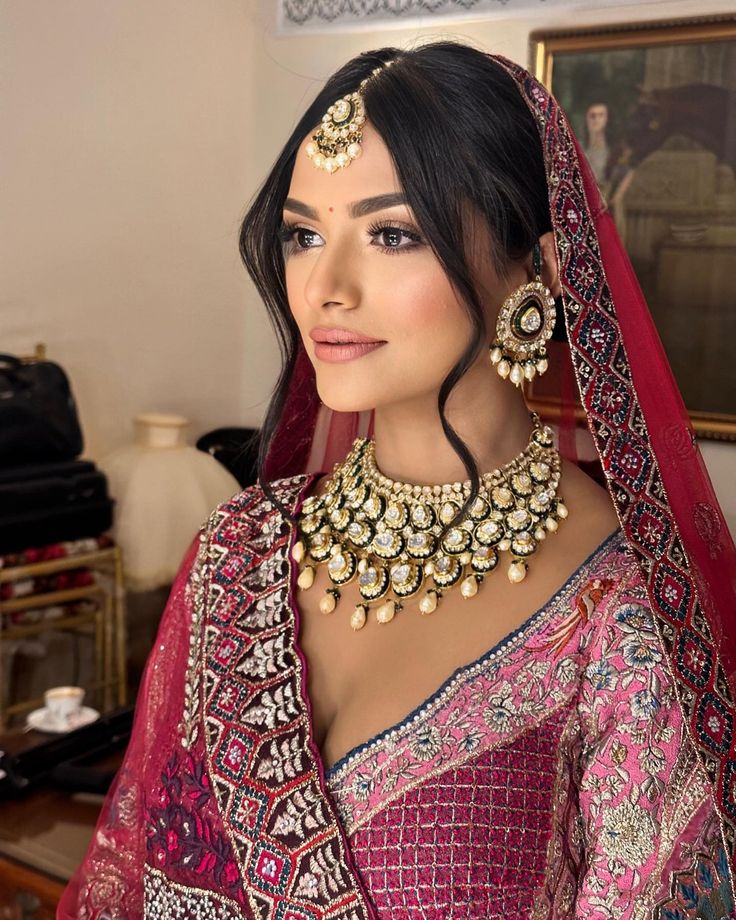 a woman wearing a red and gold bridal outfit with matching jewelry on her neck