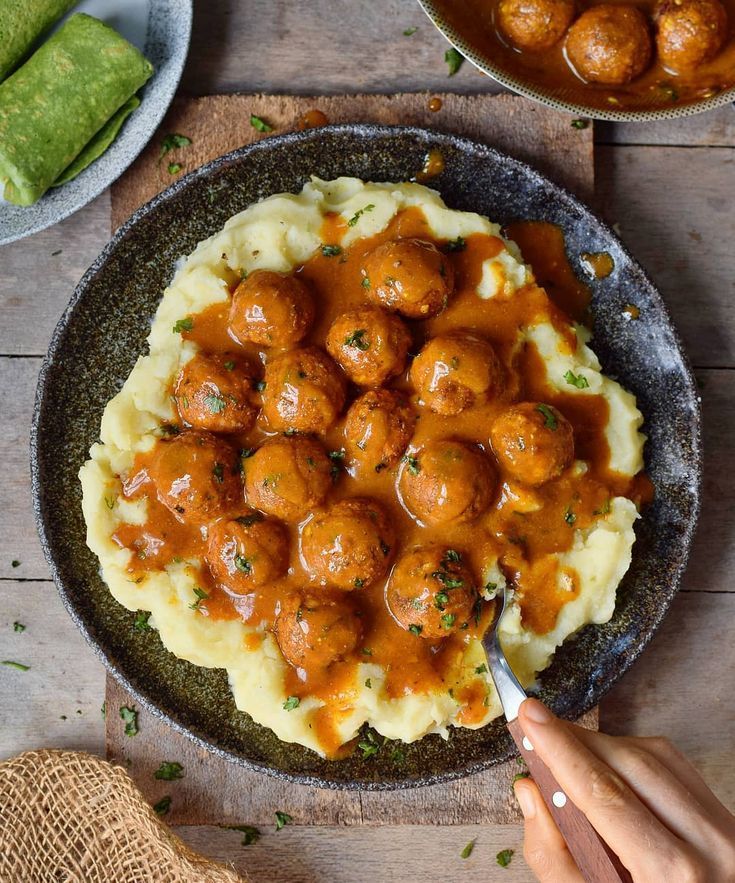 a plate with mashed potatoes covered in meatballs and gravy