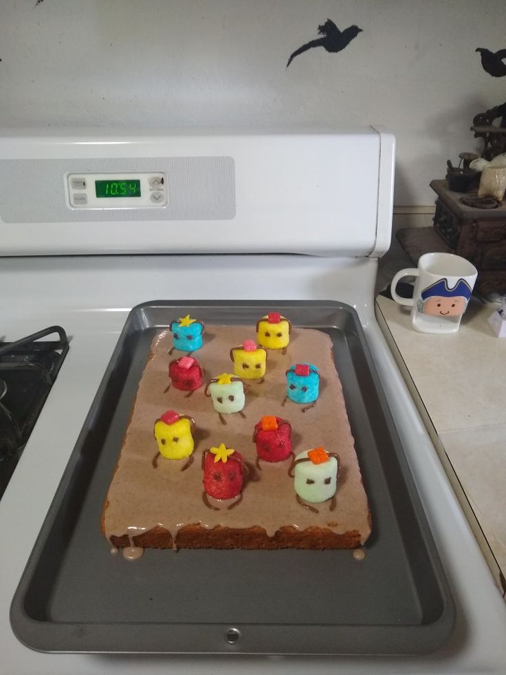 a cake with frosting on it sitting on top of a stove next to a microwave