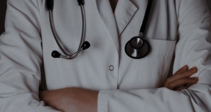 a doctor is standing with his arms crossed and wearing a white coat, black stethoscope