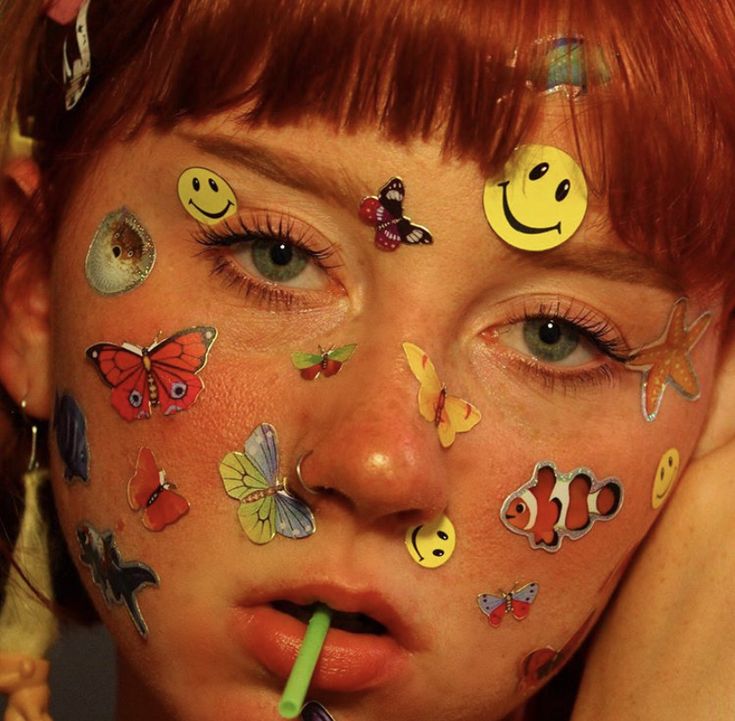 a woman with her face painted with smiley faces and other stickers on her face