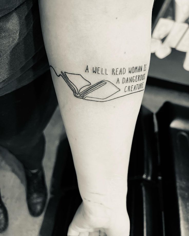 a person with a book tattoo on their left leg and the words, a well read woman is a dangerous creature