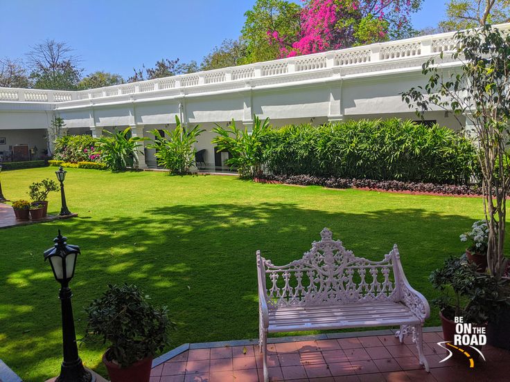 a white bench sitting in the middle of a lush green park next to a building