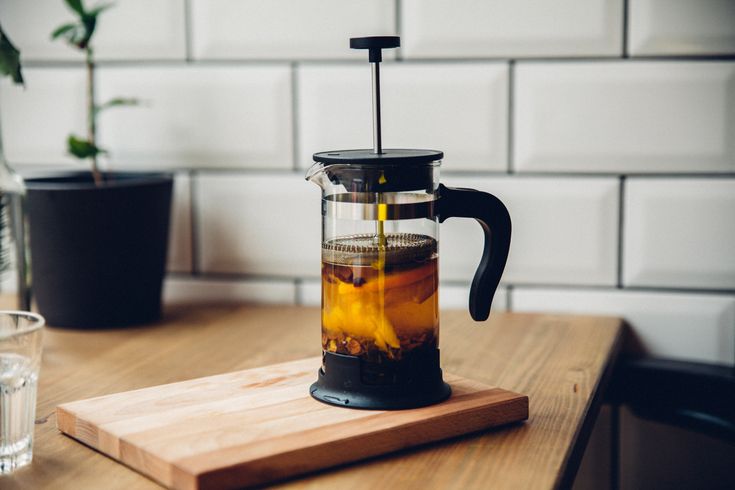 a pitcher filled with liquid sitting on top of a wooden cutting board