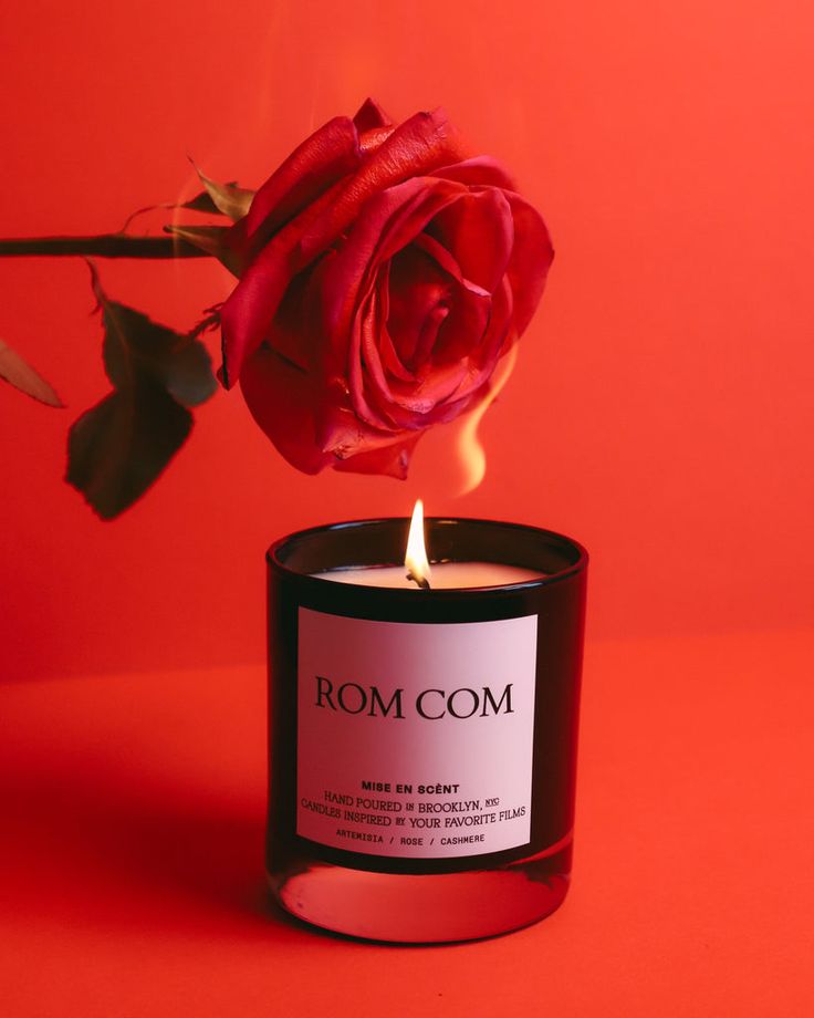 a candle that is next to a rose on a red background with the words room com