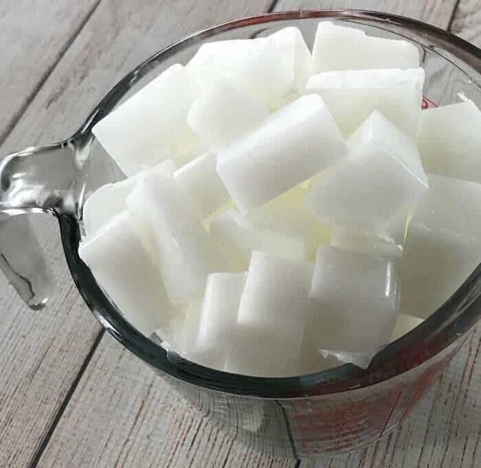 a blender filled with sugar cubes sitting on top of a wooden table next to a spoon