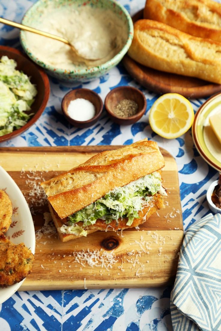 a table topped with plates and bowls filled with food on top of a wooden cutting board