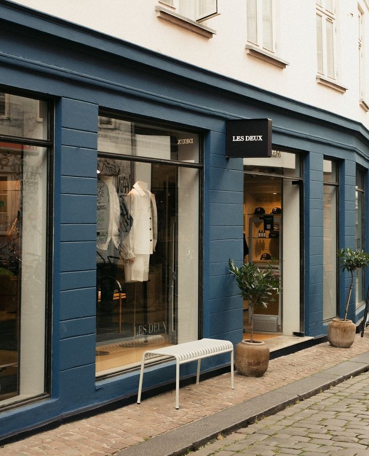 a store front with blue painted walls and white chairs on the sidewalk in front of it