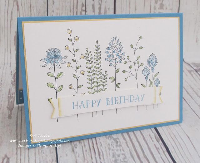 a happy birthday card with flowers and ribbons on the front, sitting on a wooden table