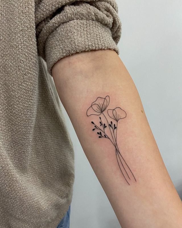 a woman's arm with a small flower tattoo on the left side of her arm