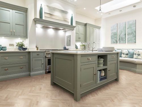 a large kitchen with green cabinets and wood flooring, along with a breakfast nook