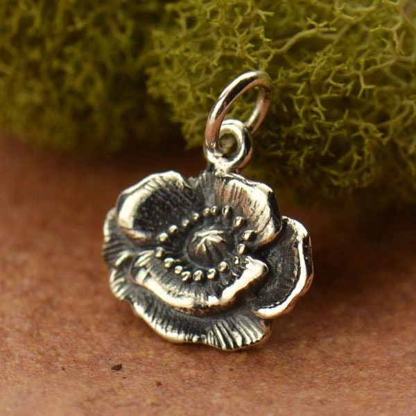 Poppy Charm in Sterling Silver. Sterling Silver Vintage Inspired Poppy Flower Charm. This beautiful poppy is one of the few flower charms we offer that is wider than it is long. It is a fresh perspective that really works. Pair with all your chubby gemstone beads. Flower petals are delicately textured with lines and dot details. This beautiful charm is great for earrings, charm bracelets & necklaces. Design on one side only. Length measure includes 5 mm soldered jump ring. Size: 15 mm x 12 m Poppy Necklace, Beads Flower, Mini Charm, Feather Pendant, Feather Charms, Themed Jewelry, Sterling Silver Flowers, Birthstone Charms, Charm Set