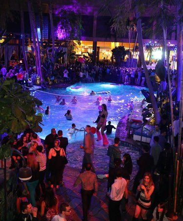 a crowd of people standing around a pool at night