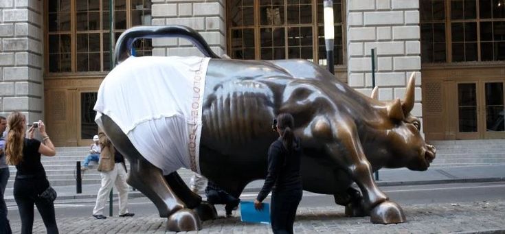 a woman standing next to a statue of a bull on the side of a road