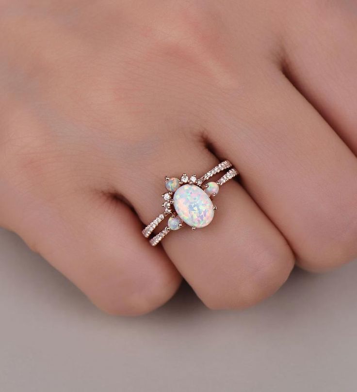 a woman's hand with a white opal and diamond ring on her finger