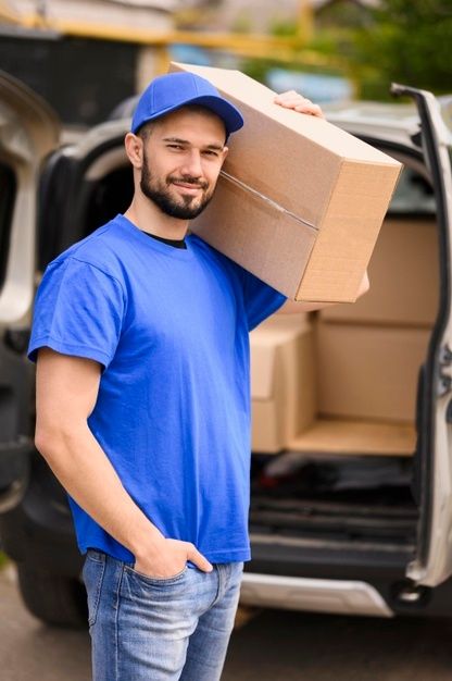 a man with a cardboard box on his head standing in front of the back of a van