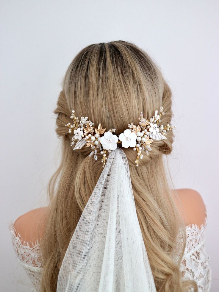 a woman with long blonde hair wearing a veil and flowers in her hair is seen from the back