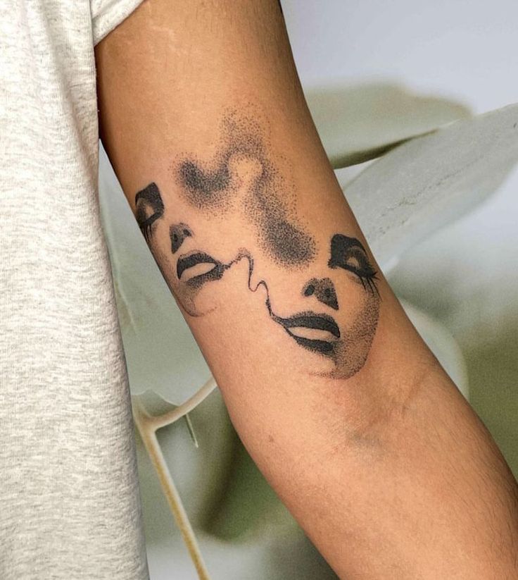 a person with a face tattoo on their arm