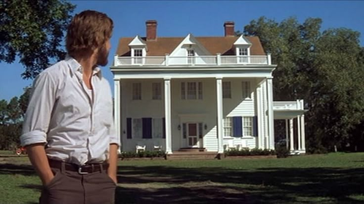 a man standing in front of a large white house