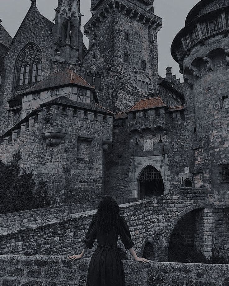 a woman standing in front of an old castle