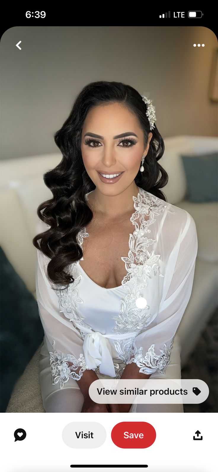 a woman with long hair wearing a white dress and pearls on her head is smiling at the camera