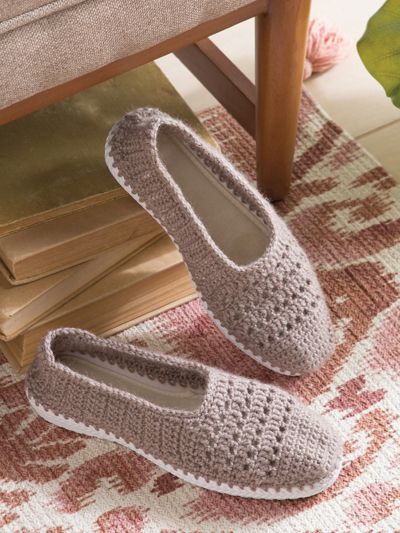 a pair of crocheted slippers sitting on top of a rug