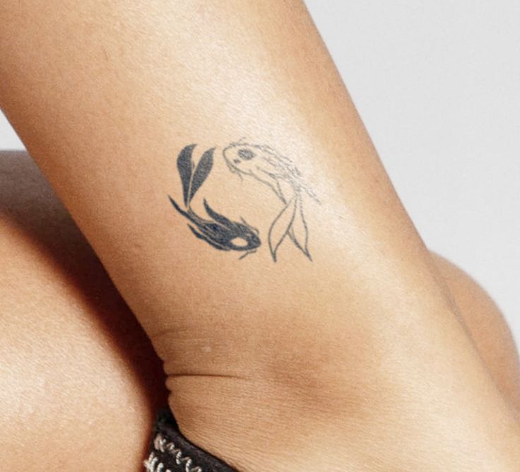 a woman's leg with a tattoo on her left arm and an image of a fish in the middle