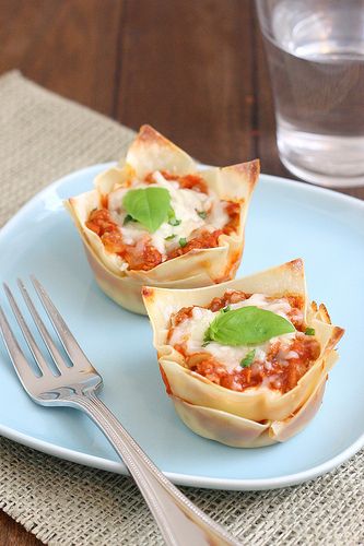 two mini pizzas on a blue plate with a fork and glass of water in the background