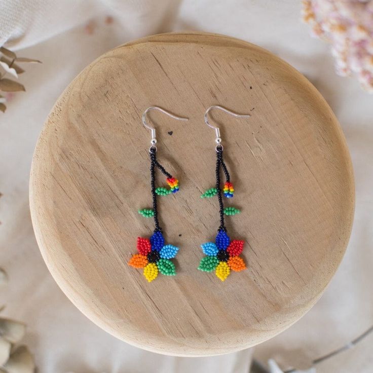 a pair of colorful beaded earrings sitting on top of a wooden table